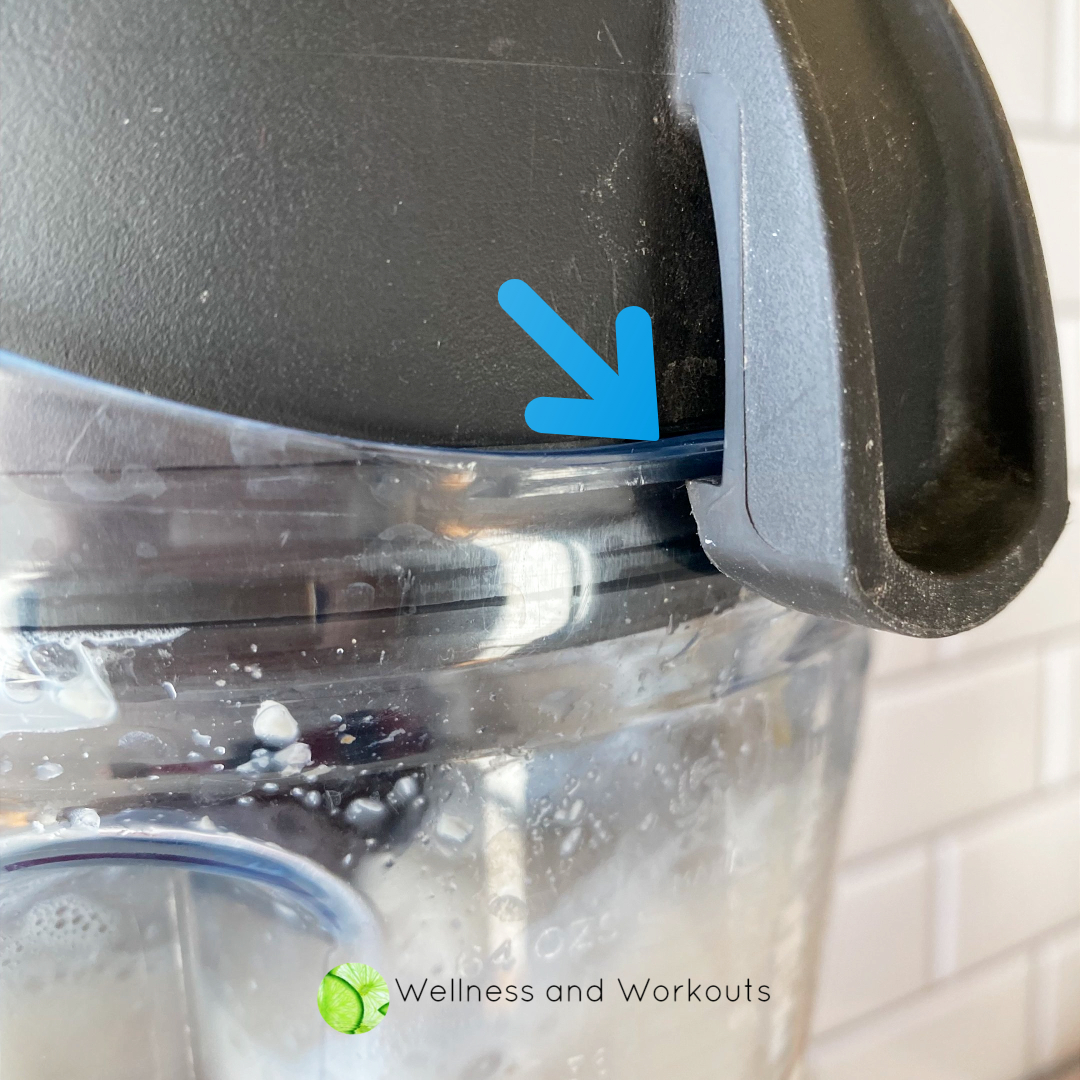 This is a close-up shot of the lid of my Vitamix, with an arrow indicating where the lid should be latched on so it stays in place while blending.