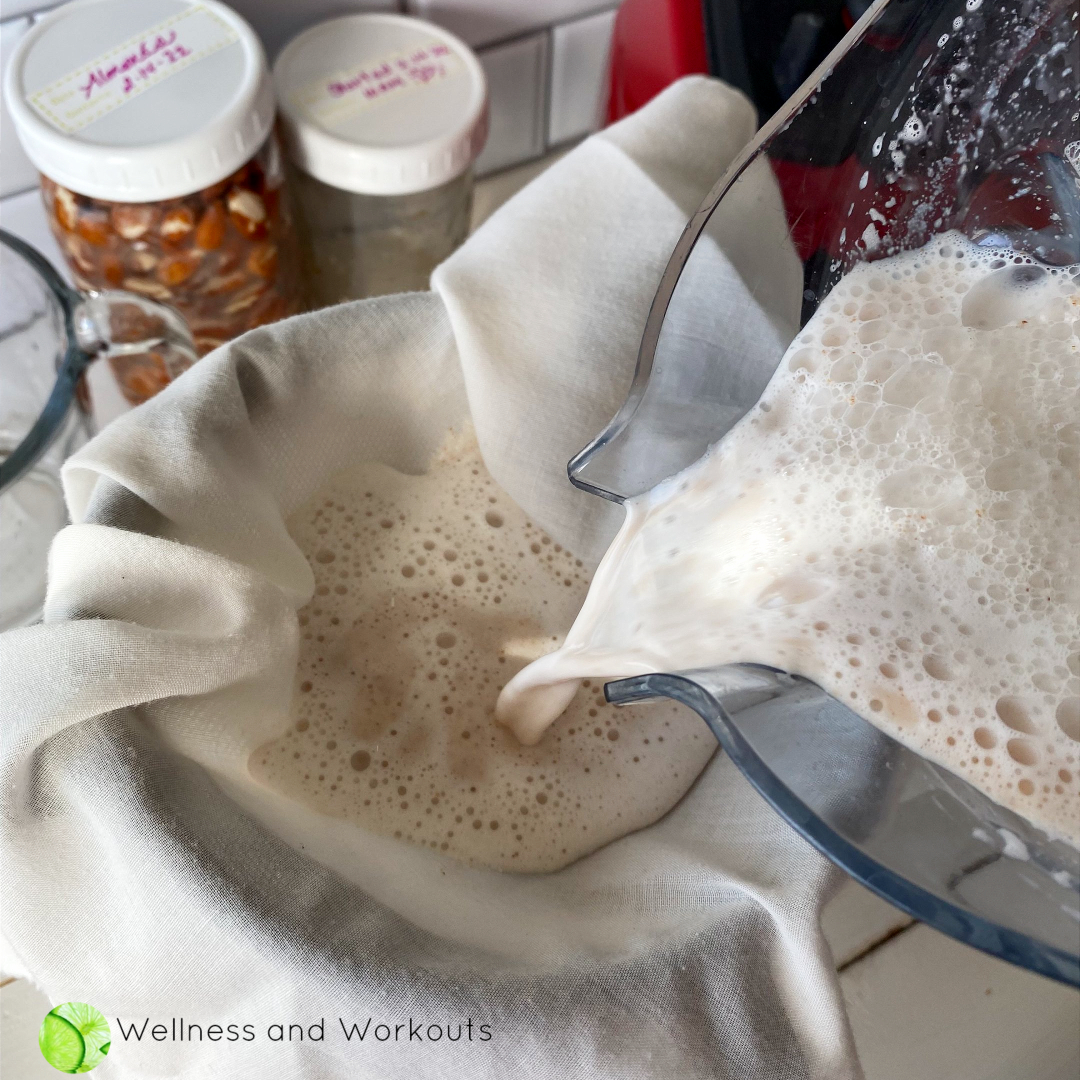 Pouring almond milk into a muslin cloth strainer with a mason jar underneath.