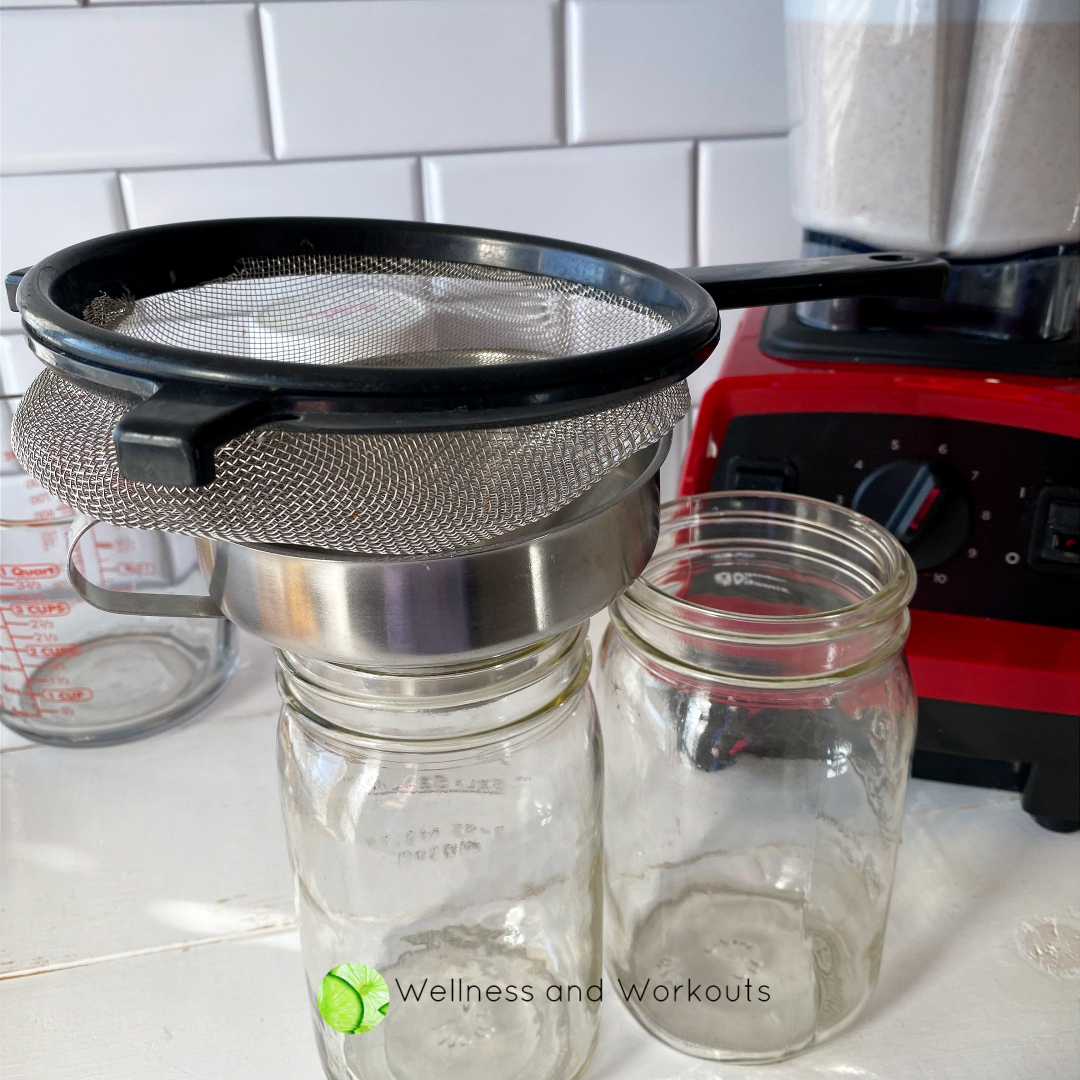 A wire strainer sits atop a canning funnel and glass mason jar.